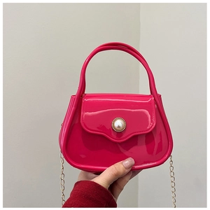 Detail view of rose red jelly handbag featuring a pearl buckle and gold chain strap