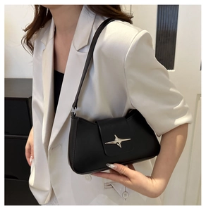 Close-up of black faux leather underarm bag featuring a silver star metal buckle