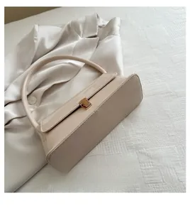 Détail du fond plat et du profil structuré du sac en cuir verni de couleur crème