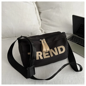 Detail of black oxford shoulder bag featuring trendy letter embroidery and wide strap