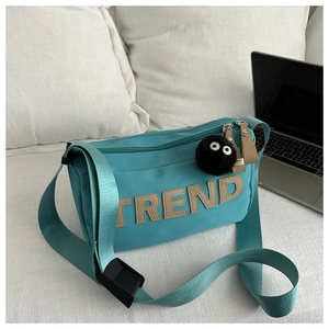 Detail of teal canvas travel bag with TREND embroidery and plush monster charm