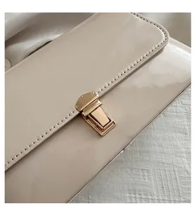 Gros plan d'un sac en cuir verni crème avec un fermoir doré et des coutures détaillées