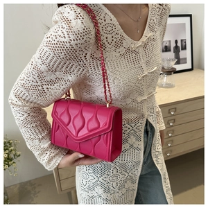Detail of rose pink quilted chain bag worn by model with casual stylish outfit