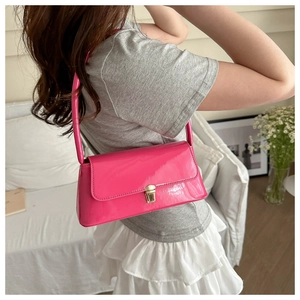 Detailed view of glossy pink patent leather underarm bag with gold metal buckle