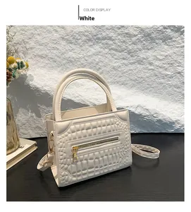 Detail of white crocodile embossed mini handbag with gold zipper and round handles