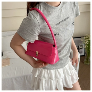 Detail of rose red patent leather baguette bag with shiny gold metal buckle lock