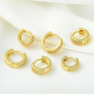 Set de boucles d'oreilles huggie dorées avec oxydes de zirconium sur soie blanche