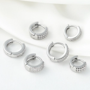 Trois paires de créoles en argent serties de zircons sur un tissu en soie blanche