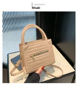 Detail of khaki crocodile pattern handbag with gold zipper and adjustable strap