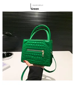 Detail of green crocodile pattern handbag with dual handles and side decorative zipper