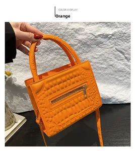 Macro shot of orange crocodile embossed texture and metal zipper detail on small handbag
