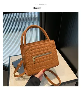 Close-up of brown crocodile pattern square handbag with metal zipper and handle