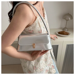 Detail of silver metallic underarm bag showing glossy finish and golden metal clasp