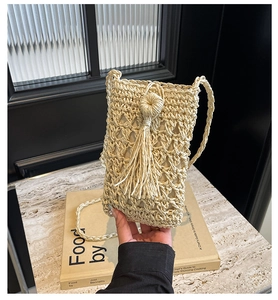 Détail du sac bandoulière en paille tissé à la main avec motifs ajourés et longs glands