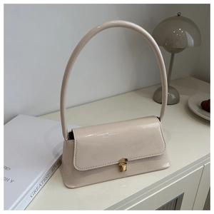 Detail of a minimalist cream glossy leather shoulder bag with long handle and gold buckle