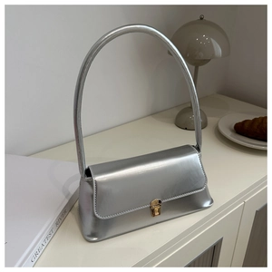 Detail of silver baguette bag with golden metal buckle and minimalist curved handle design