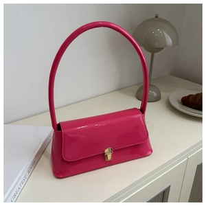 Detail of glossy hot pink patent leather shoulder bag with elegant gold metal clasp