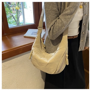 Detail of beige nylon hobo bag with wide shoulder strap and woven zipper puller
