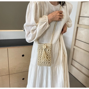 Détail du sac de téléphone en paille ajourée avec glands beiges et texture tressée