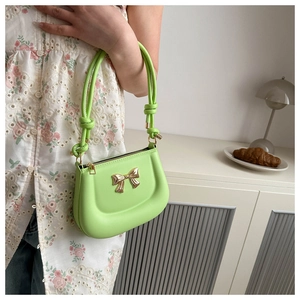 Detail of lime green crossbody bag with golden bow and knotted handle detail