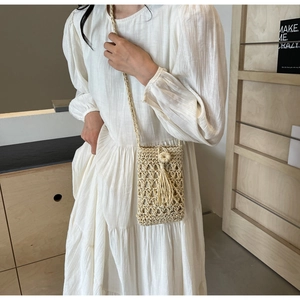 Détail d'un sac à bandoulière en paille évidée avec boucle en bois et longs glands