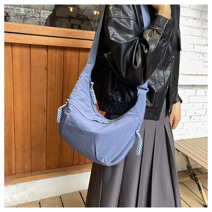 Sky blue nylon crescent bag with woven zipper pull detail worn by a model in lifestyle setting