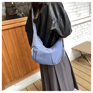 Blue nylon crescent dumpling bag with stylish wide shoulder strap and woven zipper detail