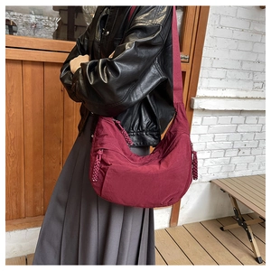 Detail of burgundy nylon crescent bag showing durable fabric and wide shoulder strap