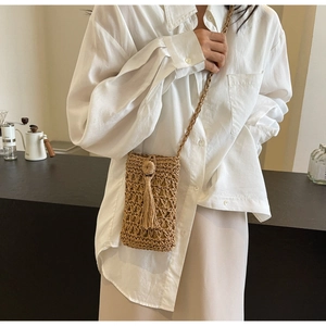 Gros plan détaillé du sac en paille tressé avec des franges et des textures naturelles