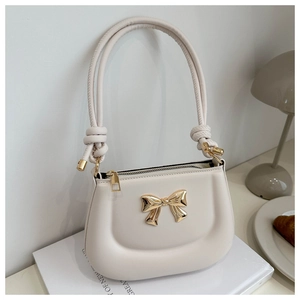 Detail of cream PU leather handbag with gold bow buckle and knotted handle design