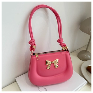 Macro detail of hot pink leather handbag with gold bow hardware and knotted handle design