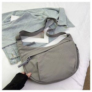 Detail view of grey nylon dumpling bag with adjustable wide strap and woven zipper pull