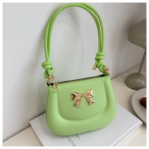 Close-up of bright green matte leather bag with golden metal bow and knotted shoulder strap