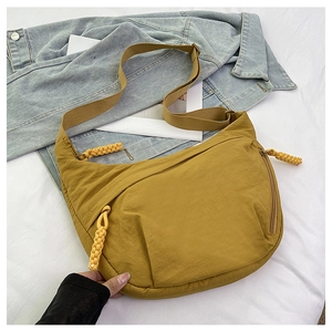 Detail of mustard yellow nylon crossbody bag featuring handmade woven knot zip pulls