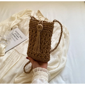 Détail d'un sac de téléphone en paille tissé à la main avec maille et glands décoratifs