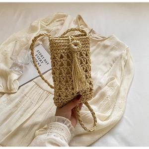 Détail d'un sac bandoulière en paille tissé à la main avec glands et fine bandoulière