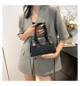 Close-up of black crocodile pattern handbag featuring a luxury rhinestone bottom finish