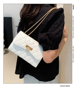 Close-up of the white quilted leather texture with a gold square clasp on a shoulder bag