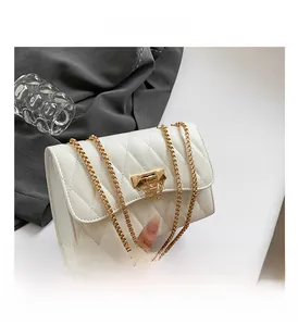 Close-up of white quilted leather crossbody bag with gold pyramid stud lock and chain