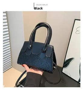 Detail of black leather crossbody bag with scale texture and smooth upper finish