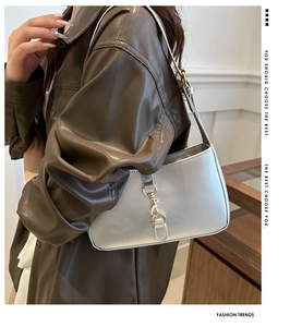 Silver crescent underarm bag with gold clasp shown on a model in a leather shirt