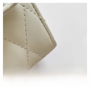 Close-up of beige quilted leather texture and fine stitching on the shoulder bag