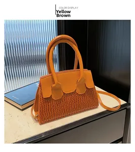 Detail of yellow-brown faux crocodile skin handbag with top handles and shoulder strap