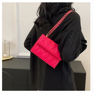 Gros plan du sac bandoulière rose fuchsia avec matelassage en gouttes et bandoulière chaîne