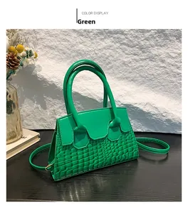 Detail of green crocodile embossed patent leather handbag with dual handles and thin strap