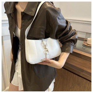 Detail of white hobo underarm bag featuring a large gold metal clasp and premium leather