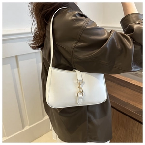 Detail of white leather hobo bag featuring a gold metal hook closure and slim shoulder strap