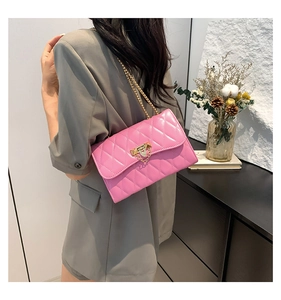 Detail of rose pink quilted crossbody bag with gold chain strap on a model's shoulder