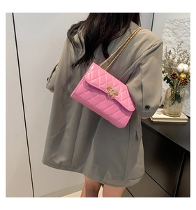 Detail of pink quilted crossbody bag with gold chain strap and rivet lock on model