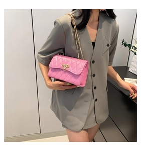 Close-up of pink quilted chain bag with gold metal lock on grey blazer outfit